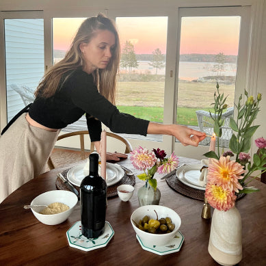 woman lighting candle on wood dining table