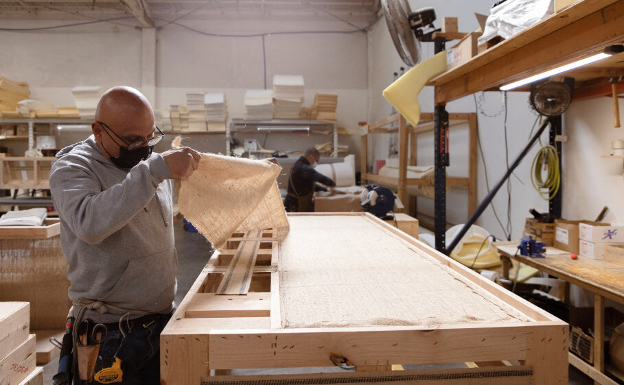 Person building a Medley sofa frame by hand and affixing a natural jute lining.