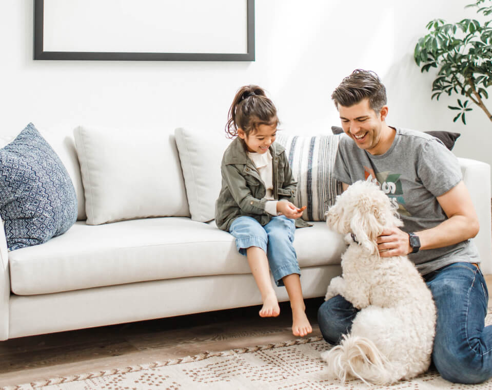 father and daughter with dog on sofa