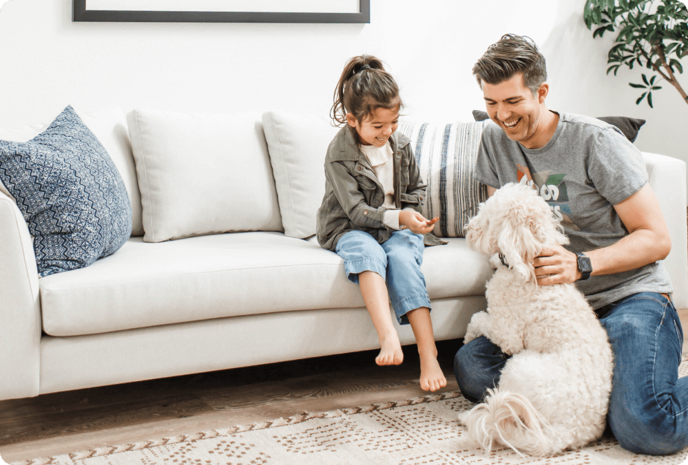 daughter and father on white sofa with dog