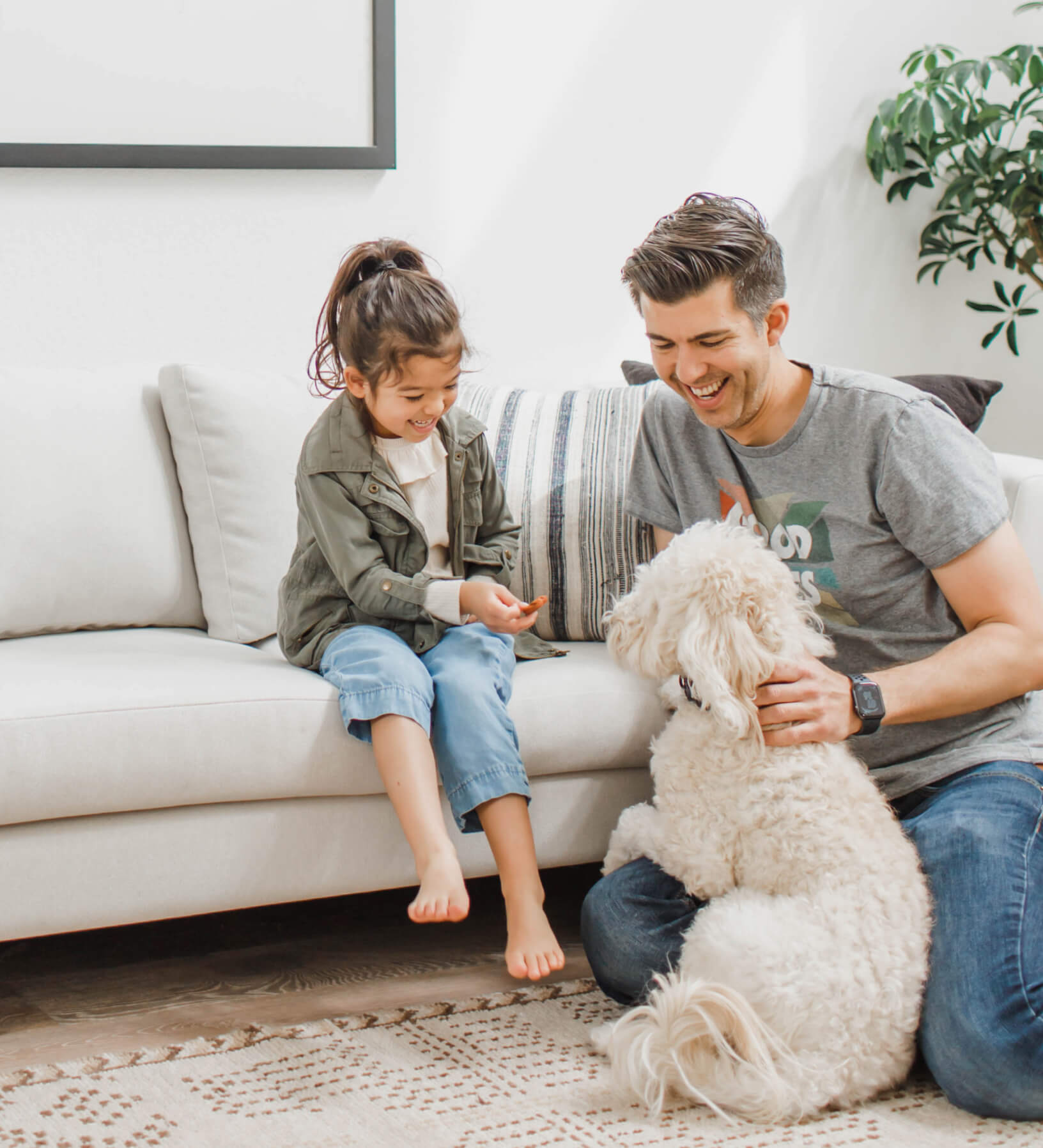 Daughter and father with white dog on white dekayess sofa