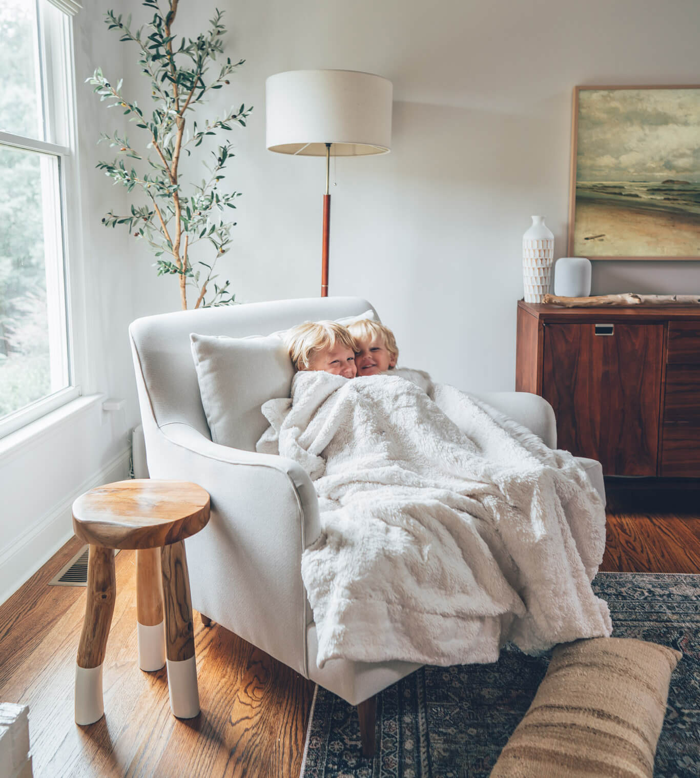 Small children snuggled up under a blanket in Medley's Kaydan Chair