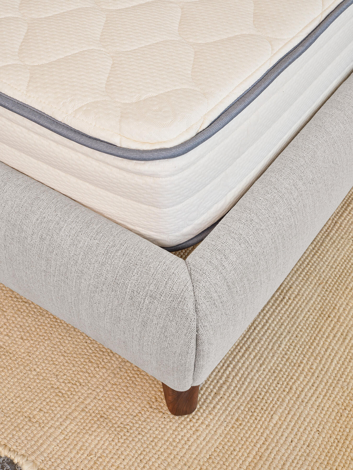 Corner view of a boxed upholstered bed frame with the mattress