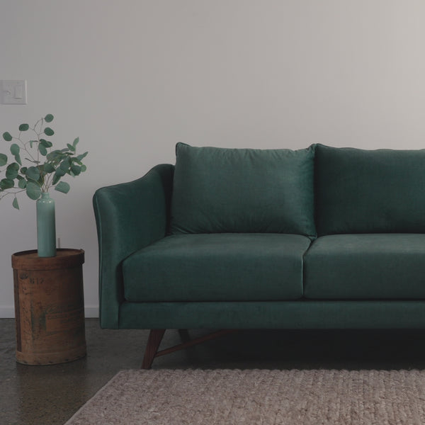 woman sits on green gio sofa